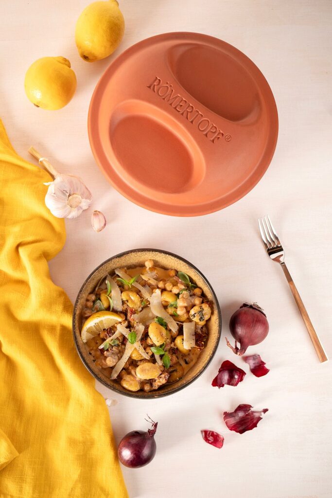 Gnocchi-Kichererbsen-Bowl mit getrockneten Tomaten, Parmesan und Basilikum, daneben der Römertopf Multi-Bräter-Deckel