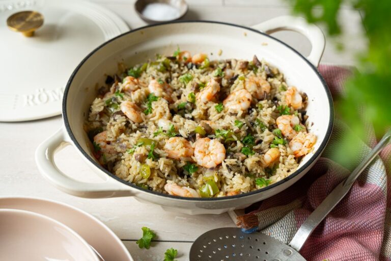 Garnelen und Reis mit Champignons und Paprika in weißer Römertopf Schmorpfanne, garniert mit frischer Petersilie