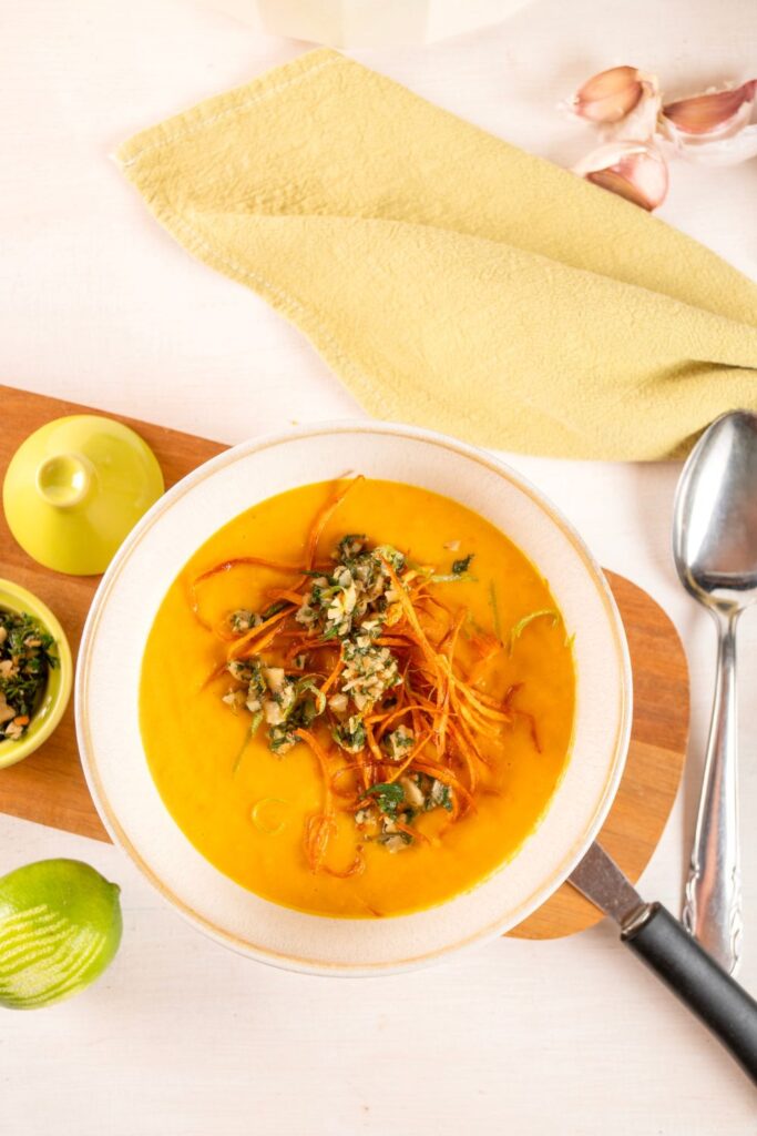 Karottensuppe mit Ingwer und Kokosmilch von oben, getoppt mit Karottenstroh, Gremolata und Limettenzesten